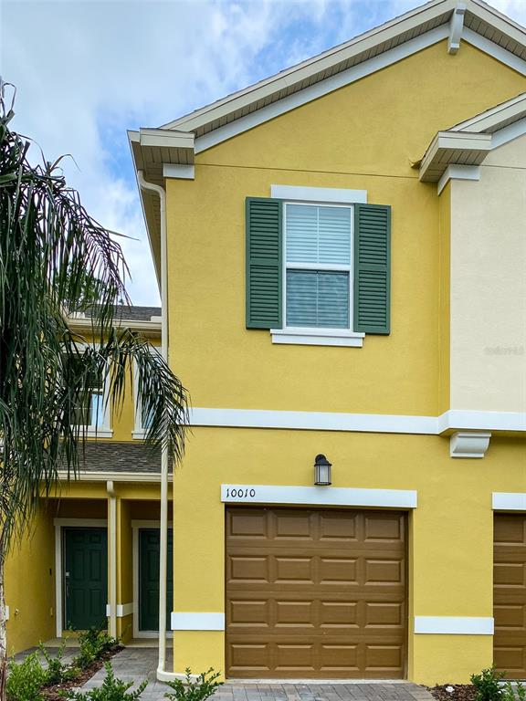 A yellow two-story townhouse features a brown garage door, green shutters, and a front entrance — 10010 RED EAGLE DRIVE, ORLANDO, FL