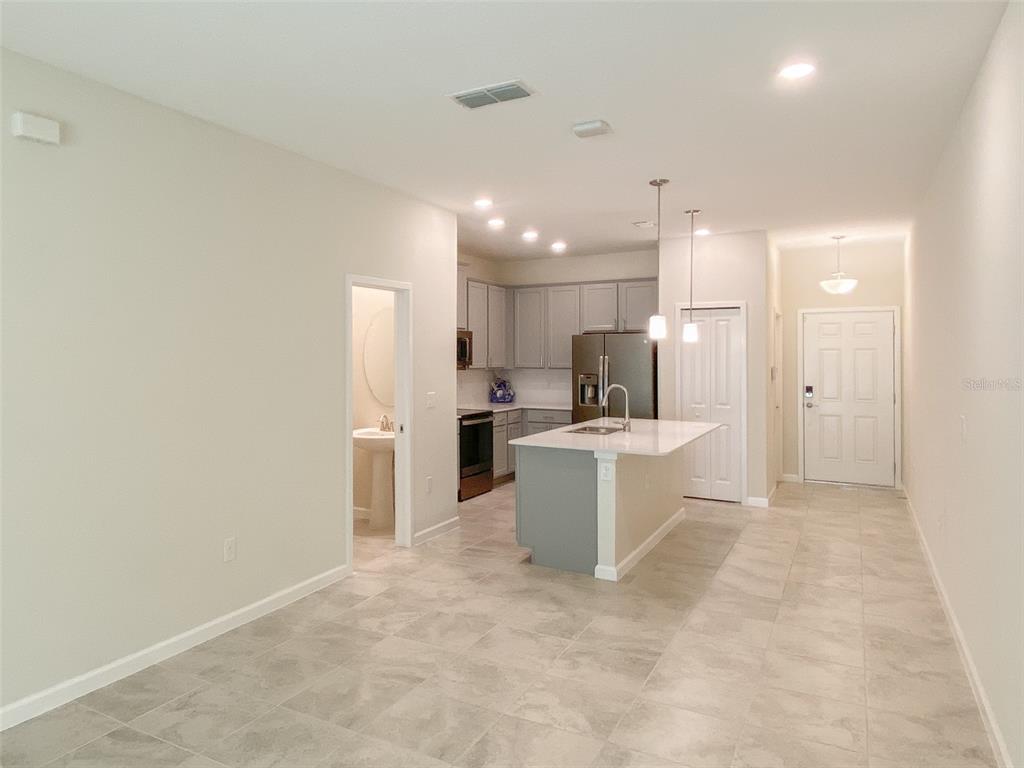 A kitchen with a gray island, stainless steel appliances, and light tile flooring — 10010 RED EAGLE DRIVE, ORLANDO, FL