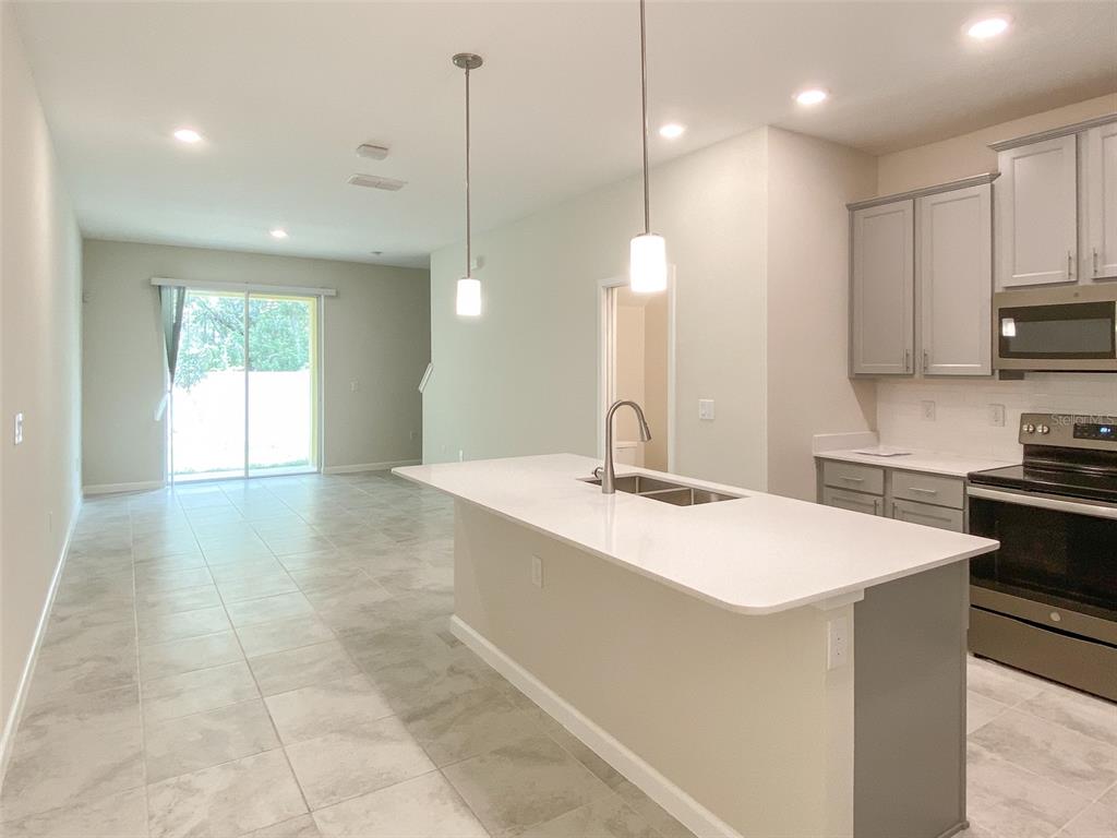 A kitchen with a white island, gray cabinets, and tile flooring opens to a living area — 10010 RED EAGLE DRIVE, ORLANDO, FL