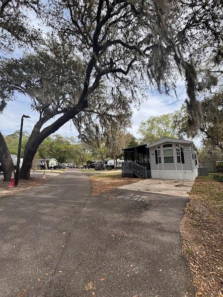 A mobile home sits on a paved lot beneath large, moss-draped oak trees — 25316 140TH PLACE NE UNIT 335, SALT SPRINGS, FL
