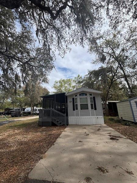 A light-colored mobile home with a screened-in porch sits on a concrete driveway — 25316 140TH PLACE NE UNIT 335, SALT SPRINGS, FL