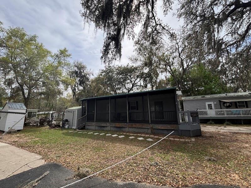 A mobile home with a large screened-in porch sits on a lot with mature trees — 25316 140TH PLACE NE UNIT 335, SALT SPRINGS, FL