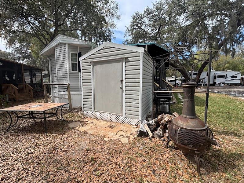 A metal storage shed sits in a yard with a table and a fire pit — 25316 140TH PLACE NE UNIT 335, SALT SPRINGS, FL