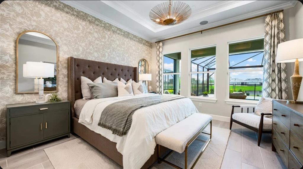 A bedroom features a tufted headboard, patterned wallpaper, a bench, and large windows with views — 7652 MOONBEAM AVENUE, SARASOTA, FL