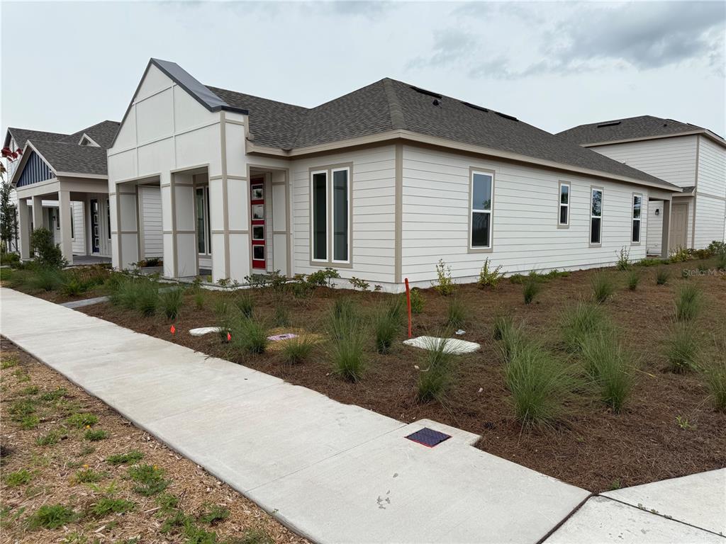 A modern single-story house with white horizontal siding and a red front door — 2949 SAILHOUSE DRIVE, ST CLOUD, FL