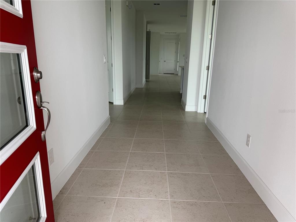 A view from an open red front door into a tiled hallway with white walls — 2949 SAILHOUSE DRIVE, ST CLOUD, FL