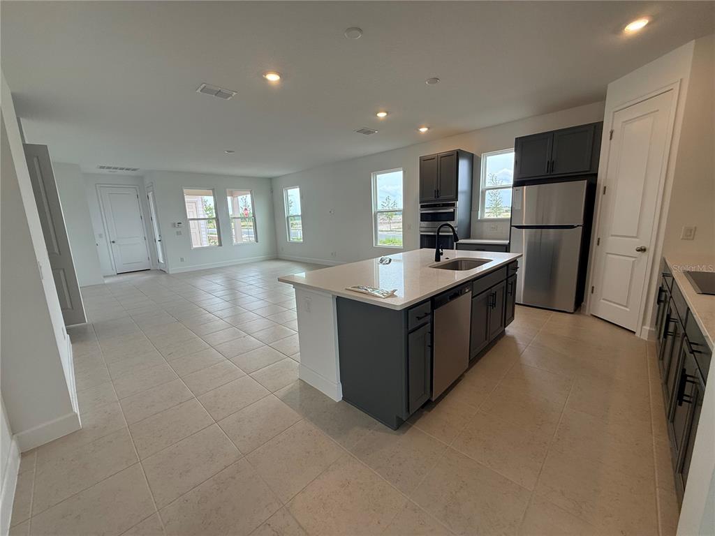 A modern kitchen with a central island, stainless steel appliances, and tile flooring — 2949 SAILHOUSE DRIVE, ST CLOUD, FL