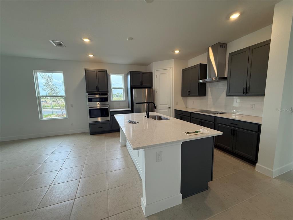 A modern kitchen features dark gray cabinets, a white island, and stainless steel appliances — 2949 SAILHOUSE DRIVE, ST CLOUD, FL