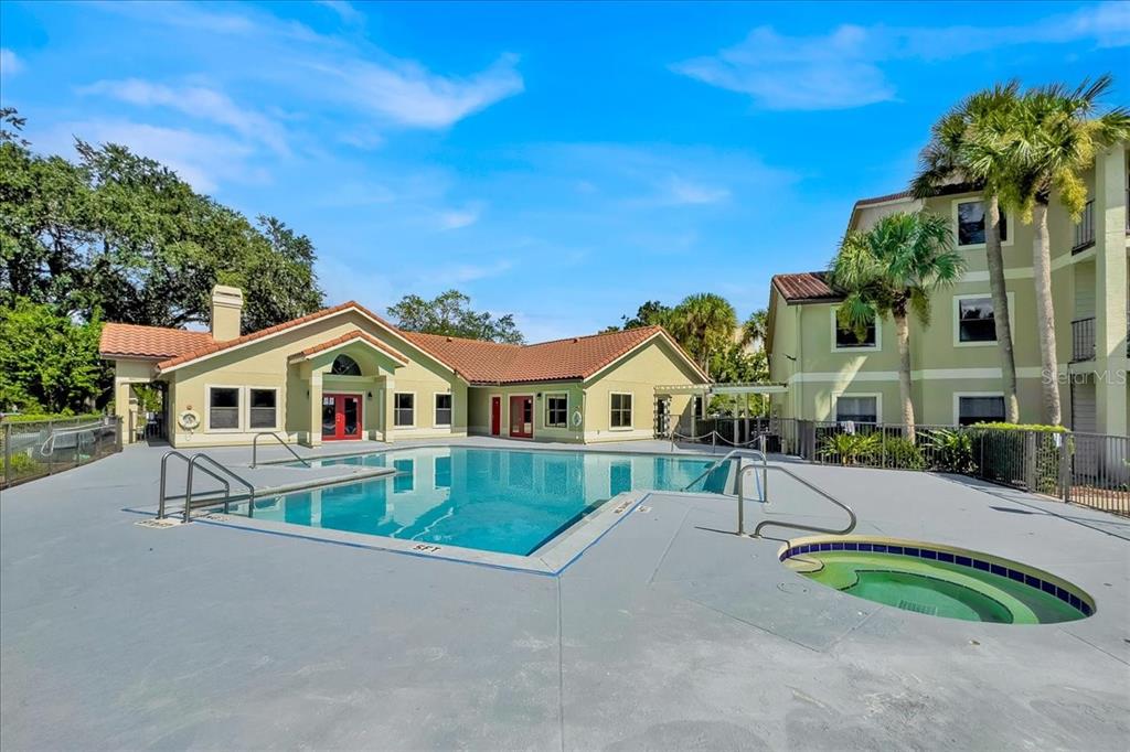 An outdoor swimming pool and hot tub are situated in front of a community building — 3032 PARKWAY BOULEVARD UNIT 307, KISSIMMEE, FL