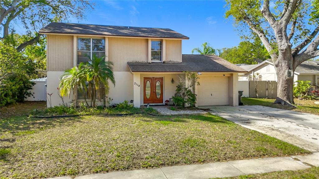 A two-story house with a tan exterior, a single-car garage, and a front palm tree — 3114 W PARIS STREET, TAMPA, FL