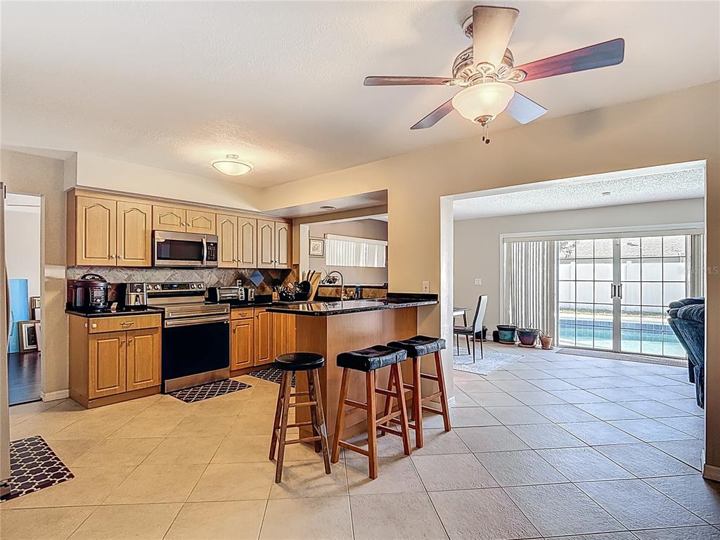 A kitchen with wood cabinets and a breakfast bar overlooks a tiled dining area — 3114 W PARIS STREET, TAMPA, FL
