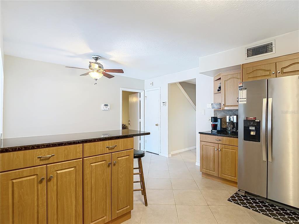 A kitchen features light wood cabinets, a dark granite breakfast bar, and stainless steel appliances — 3114 W PARIS STREET, TAMPA, FL