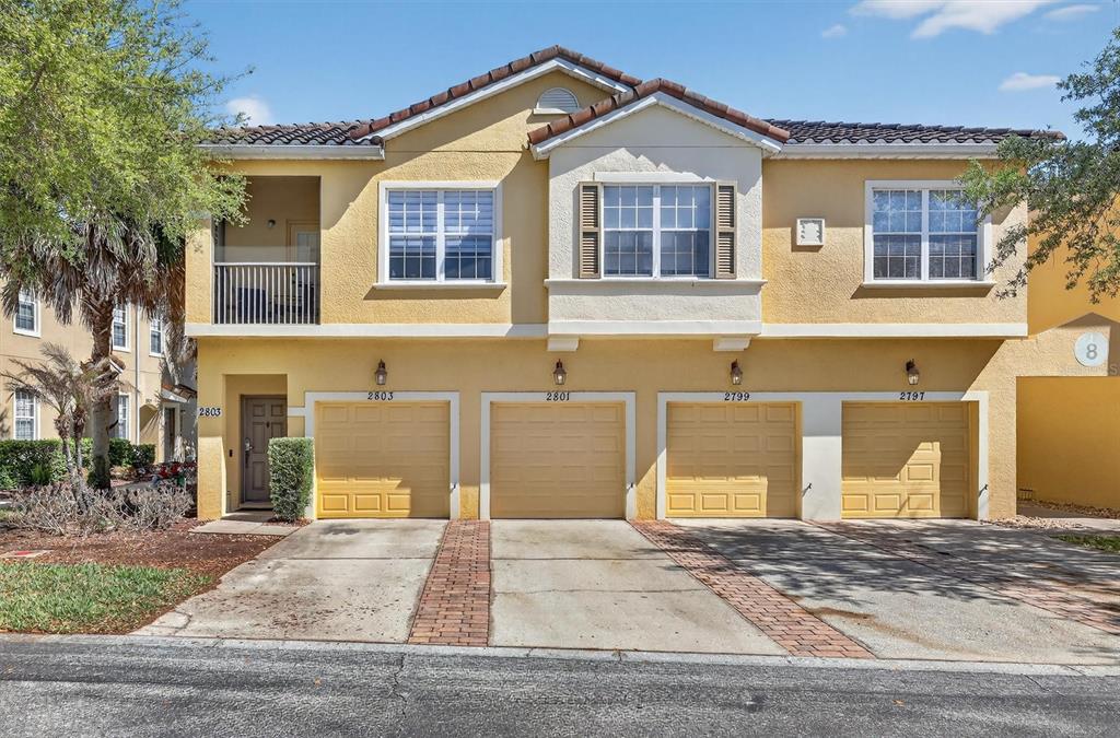 A two-story residential building features four garage doors and a second-floor balcony — 2801 OAKWATER DRIVE UNIT 2801, KISSIMMEE, FL
