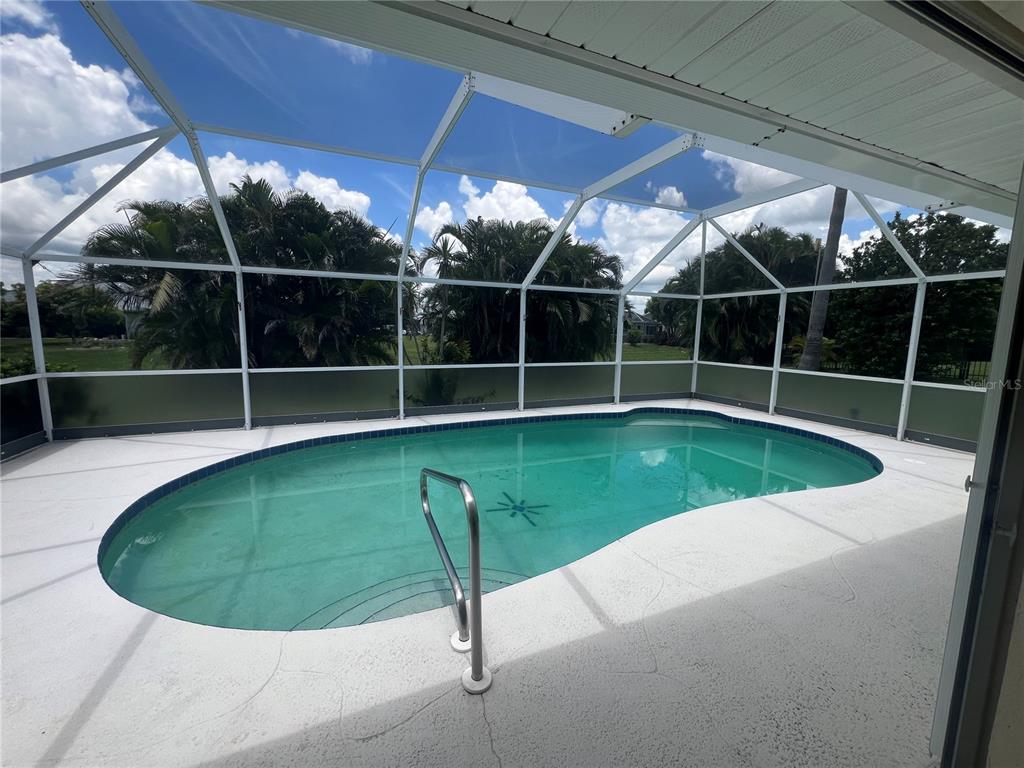 A swimming pool with a metal handrail is enclosed by a screened lanai — 1612 BLUE LAKE CIRCLE, PUNTA GORDA, FL