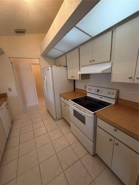 A kitchen features white cabinets, laminate countertops, a white refrigerator, and a white electric range — 1612 BLUE LAKE CIRCLE, PUNTA GORDA, FL