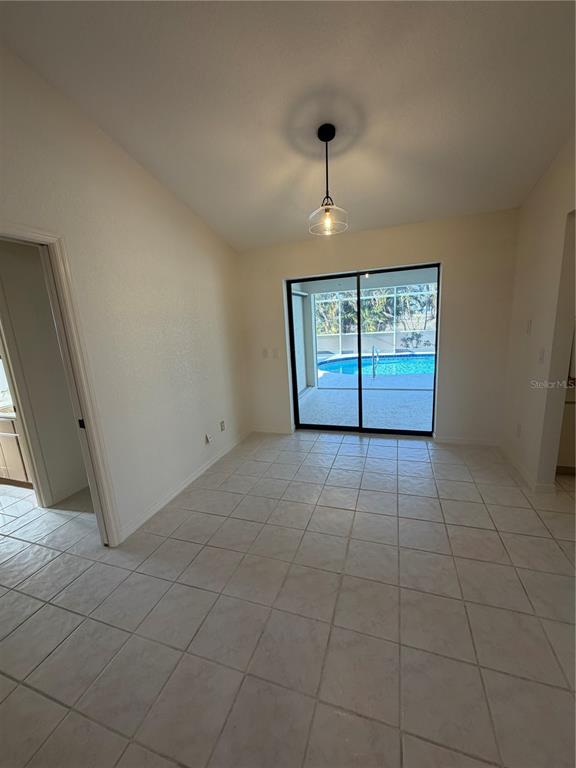 A dining area with tile flooring, a pendant light, and sliding doors opening to a pool — 1612 BLUE LAKE CIRCLE, PUNTA GORDA, FL