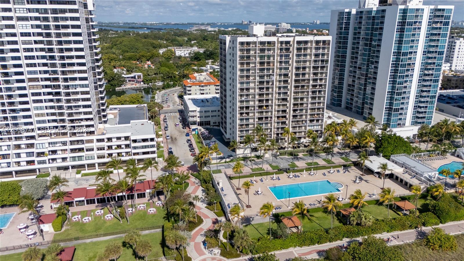 An aerial view shows three high-rise apartment buildings, a swimming pool, and landscaped grounds — 2625 Collins Ave # 803, Miami Beach FL 33140, MIAMI BEACH, FL