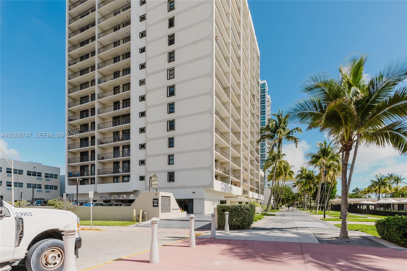 A tall, white multi-story residential building stands next to a paved walkway with palm trees — 2625 Collins Ave # 803, Miami Beach FL 33140, MIAMI BEACH, FL