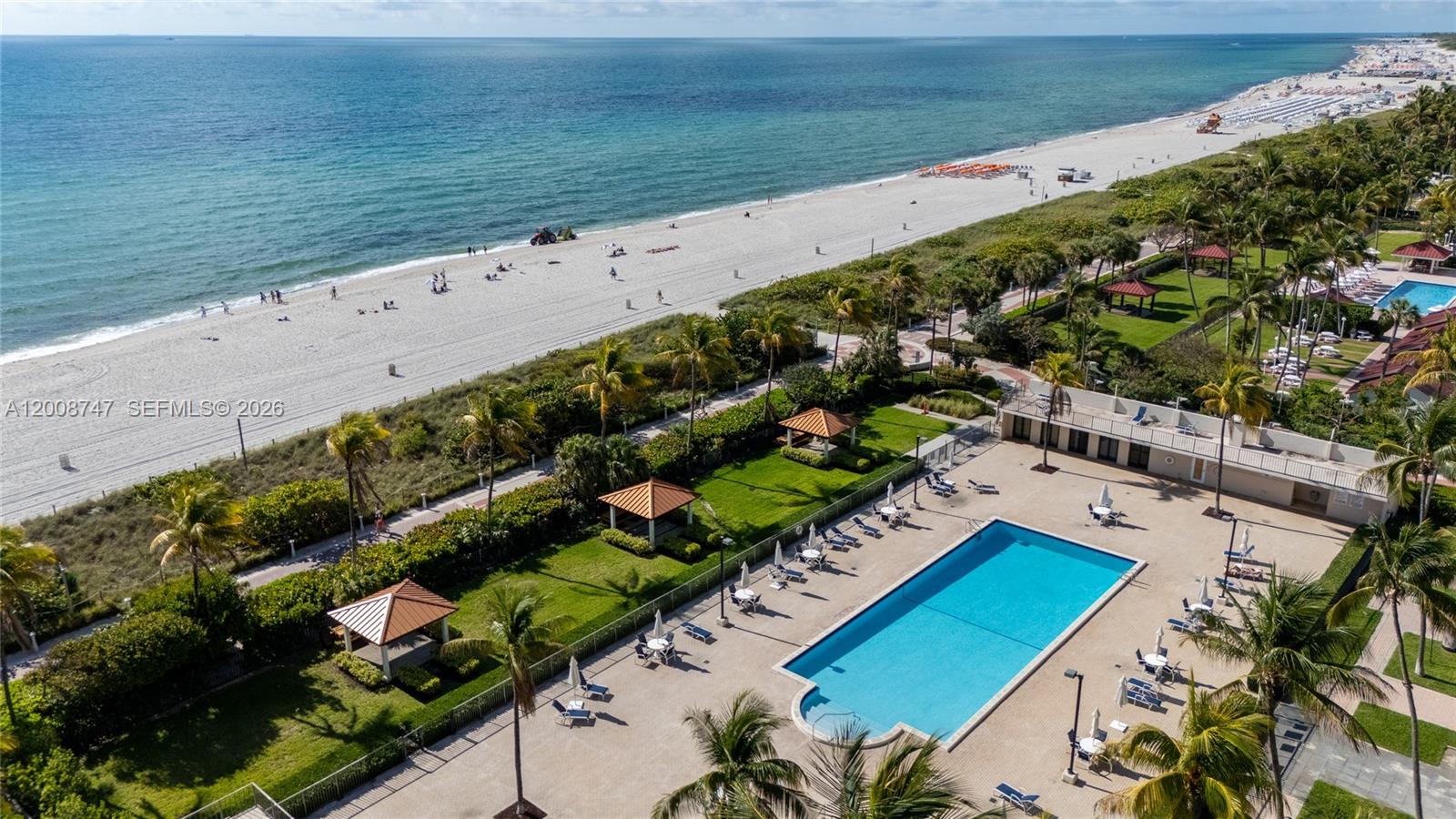 An aerial view shows a swimming pool, palm trees, and a sandy beach — 2625 Collins Ave # 803, Miami Beach FL 33140, MIAMI BEACH, FL