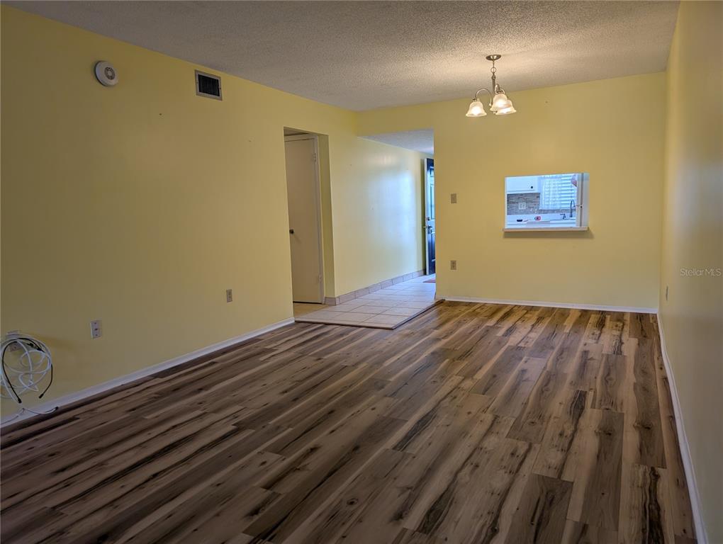 An empty room with yellow walls, wood-look flooring, a ceiling light, and a pass-through window — 4111 HERON WAY UNIT E-103, BRADENTON, FL