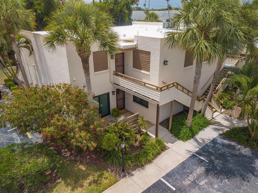 An aerial view of a two-story stucco building with palm trees and a parking lot — 193 PINENEEDLE DRIVE, BRADENTON, FL
