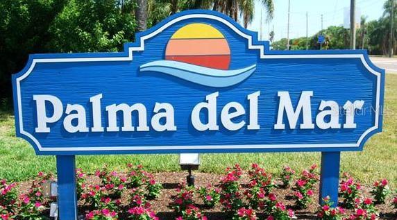 A blue sign with the text Palma del Mar stands in a garden of pink flowers — 6322 PALMA DEL MAR BOULEVARD S UNIT 305, ST PETERSBURG, FL