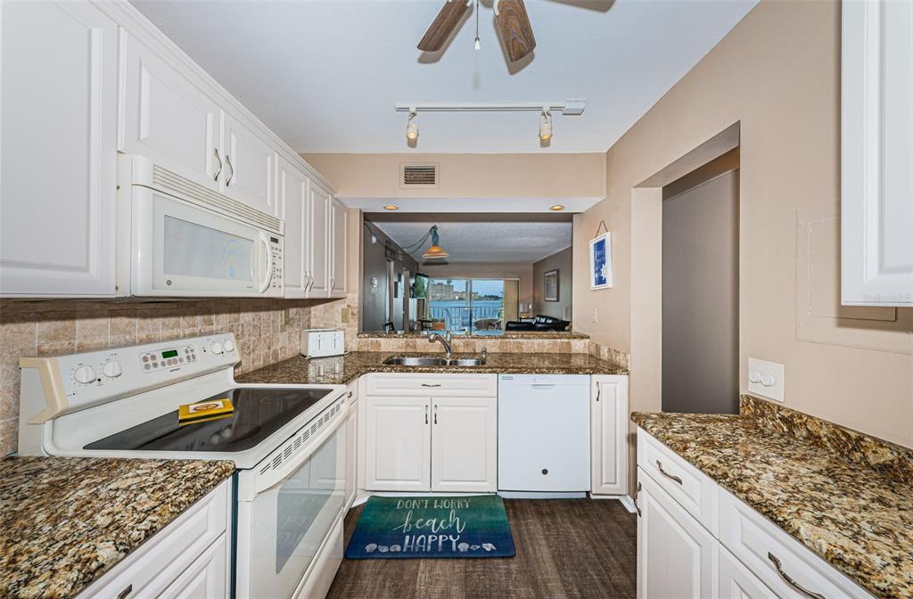 A kitchen features white cabinets, granite countertops, a white stove, and a view of water — 6322 PALMA DEL MAR BOULEVARD S UNIT 305, ST PETERSBURG, FL