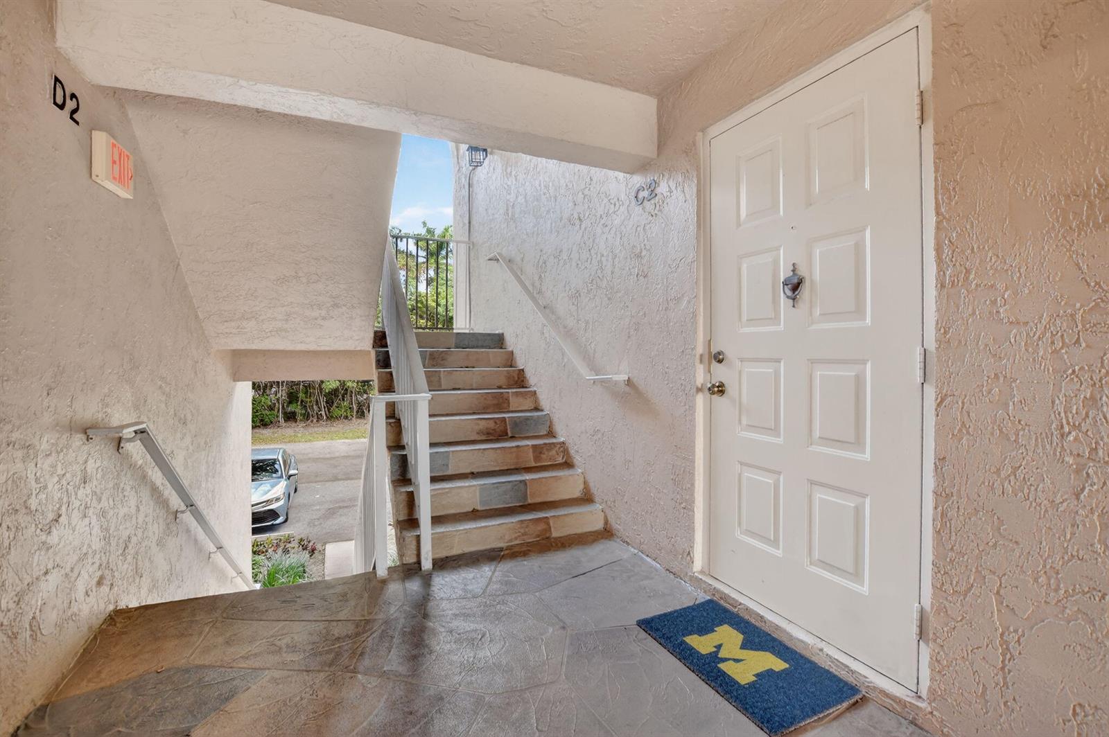 An outdoor entryway features a white door, a stone-tiled landing, and stairs leading upward — 13791 Oneida Drive # C2, Delray Beach FL 33446, DELRAY BEACH, FL