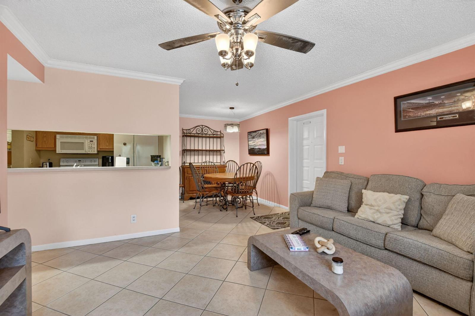 A living room and dining area with peach walls, tile floors, and a ceiling fan — 13791 Oneida Drive # C2, Delray Beach FL 33446, DELRAY BEACH, FL