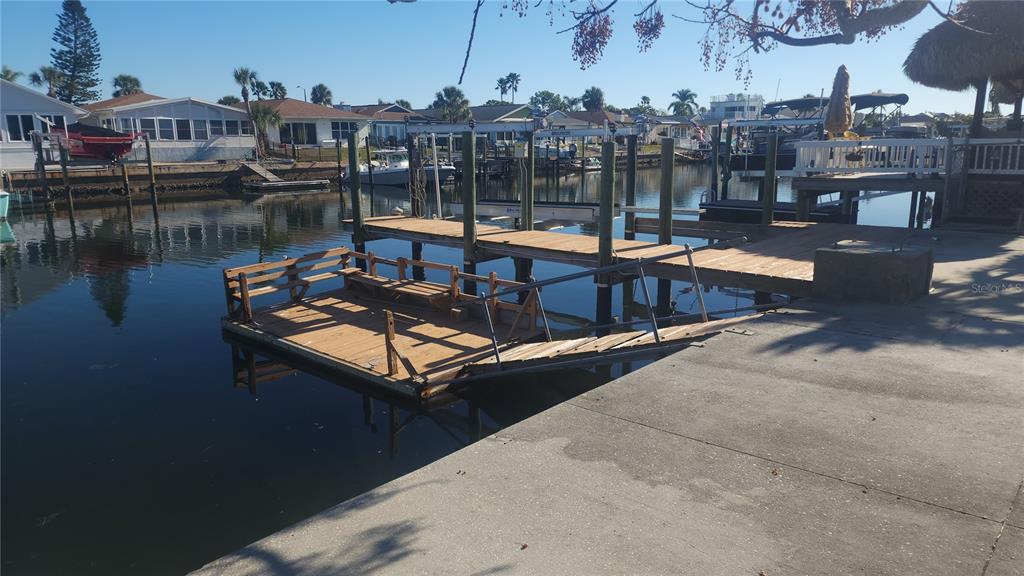 A wooden floating dock with benches is attached to a concrete seawall in a canal — 3907 FLORAMAR TERRACE, NEW PORT RICHEY, FL