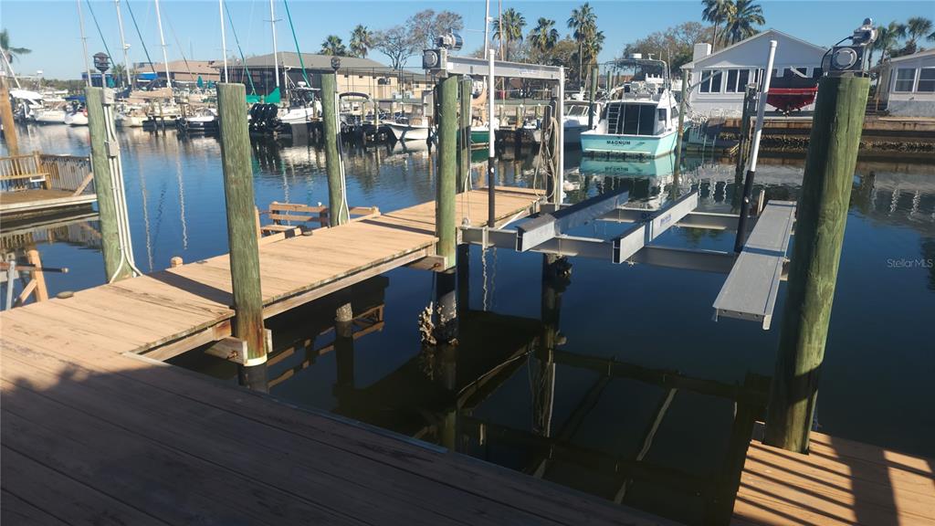 A wooden dock features a boat lift extending over the water in a residential canal — 3907 FLORAMAR TERRACE, NEW PORT RICHEY, FL