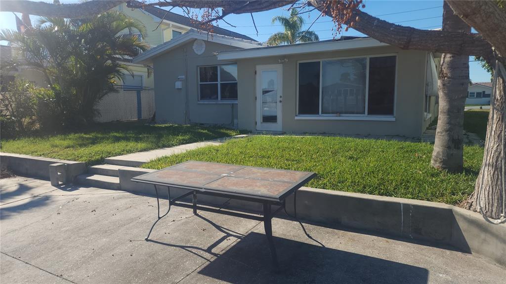 A single-story house with a lawn, concrete patio, and a metal-framed table in the foreground — 3907 FLORAMAR TERRACE, NEW PORT RICHEY, FL