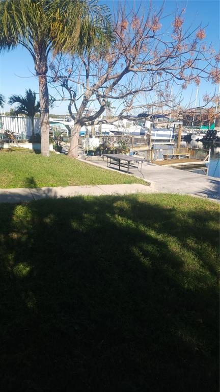 A grassy yard leads to a concrete patio with a table overlooking a boat dock — 3907 FLORAMAR TERRACE, NEW PORT RICHEY, FL