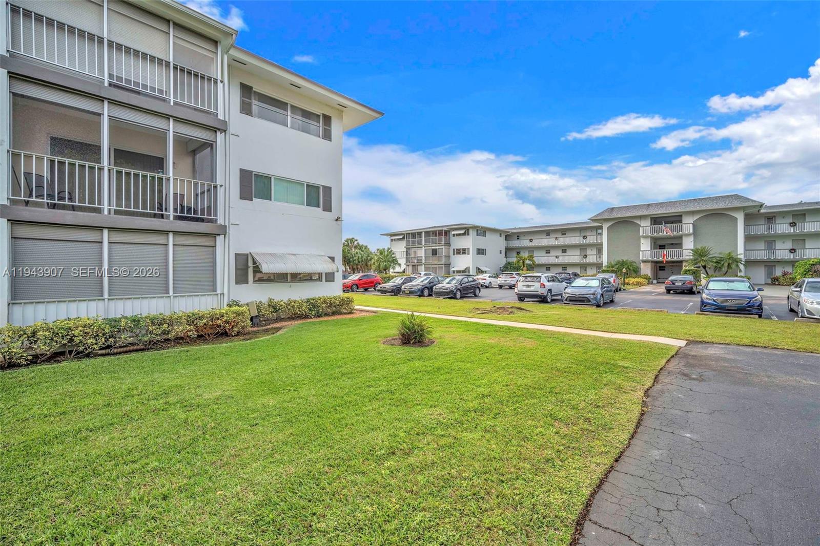 A multi-story apartment building stands next to a parking lot with several parked cars — 1201 Hillcrest Ct # 102, Hollywood FL 33021, HOLLYWOOD, FL