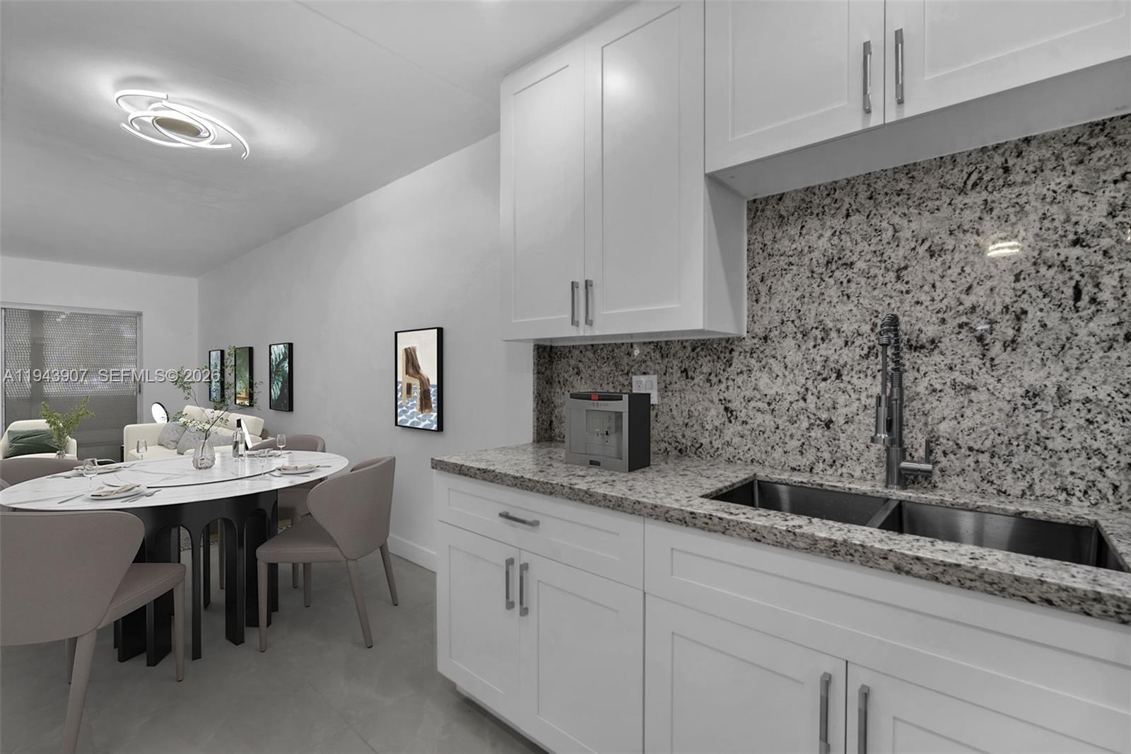 A kitchen with white cabinets and granite countertops sits adjacent to a dining area — 1201 Hillcrest Ct # 102, Hollywood FL 33021, HOLLYWOOD, FL