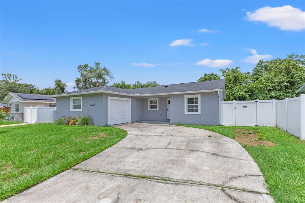 A gray single-story house with a concrete driveway, white garage door, and white vinyl fencing — 560 ROBIN HILL CIRCLE, BRANDON, FL