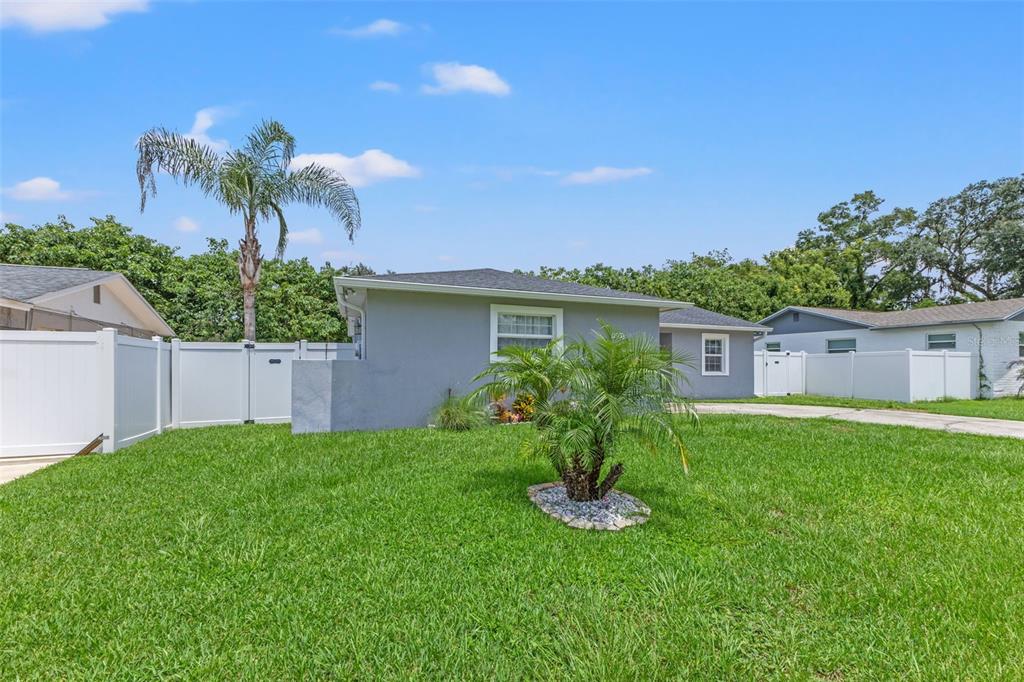 A single-story gray house with a palm tree in the front yard and white fencing — 560 ROBIN HILL CIRCLE, BRANDON, FL