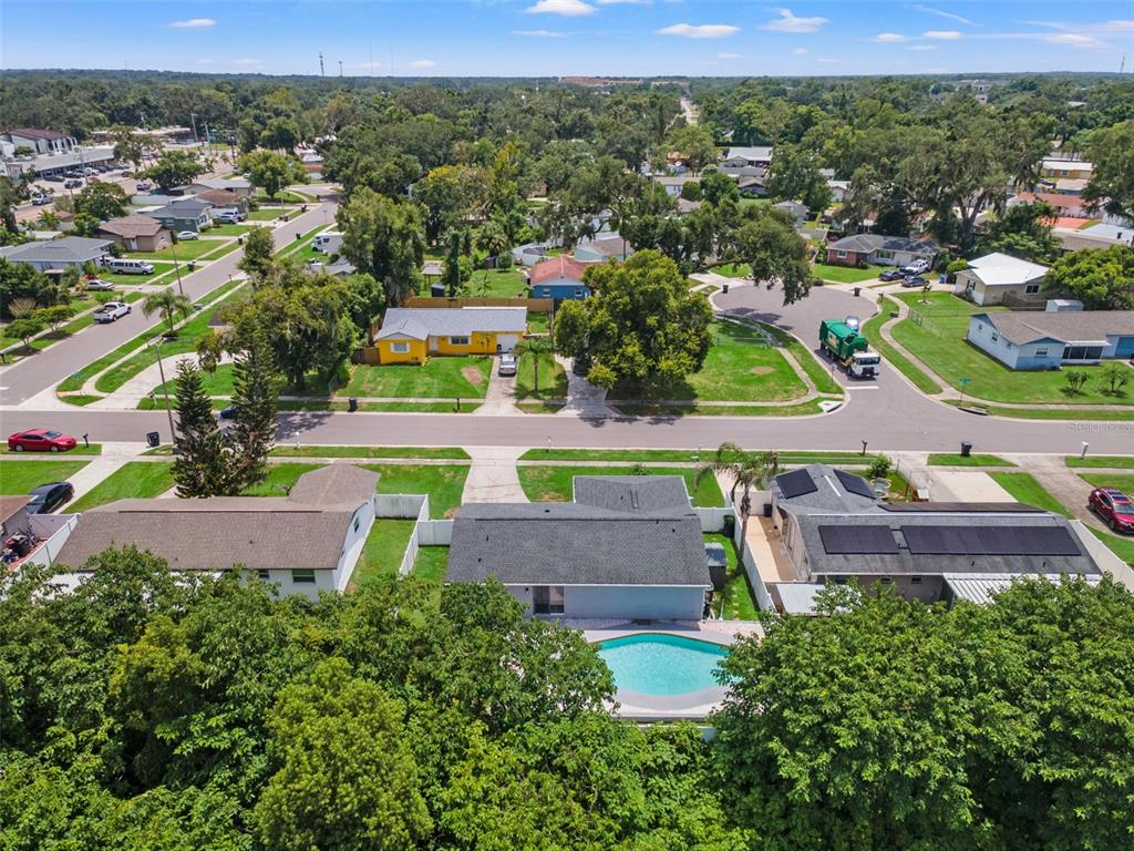 An aerial view shows a residential neighborhood with a house featuring a backyard swimming pool — 560 ROBIN HILL CIRCLE, BRANDON, FL