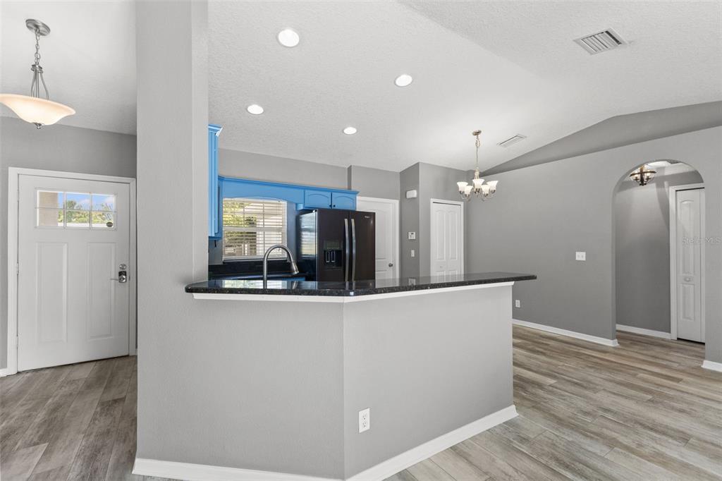 A kitchen with a breakfast bar, black appliances, and blue cabinets opens to a living area — 560 ROBIN HILL CIRCLE, BRANDON, FL