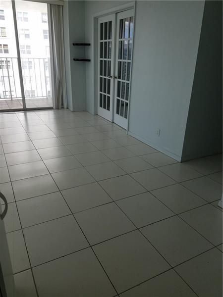 An empty room with white tile flooring, French doors, and a sliding glass balcony door — 111 Briny Avenue # 2011, Pompano Beach FL 33062, POMPANO BEACH, FL