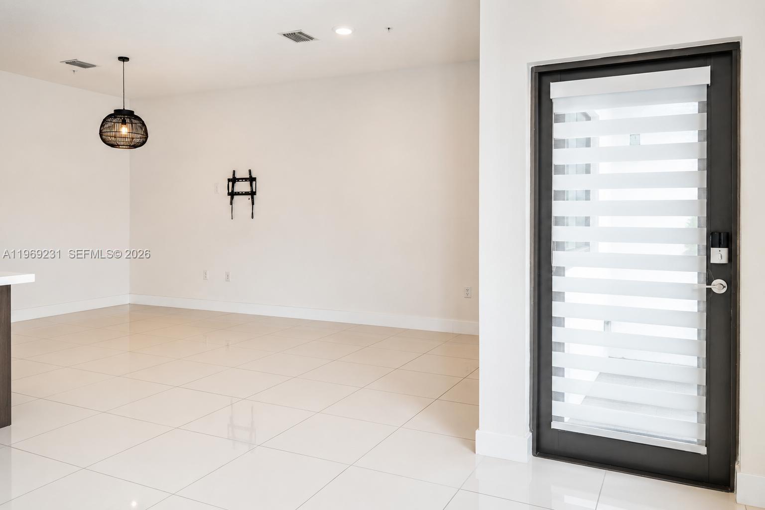 An empty room features white tile flooring, a black pendant light, and a glass door — 4745 NW 84th Ct # 14, Doral FL 33166, DORAL, FL