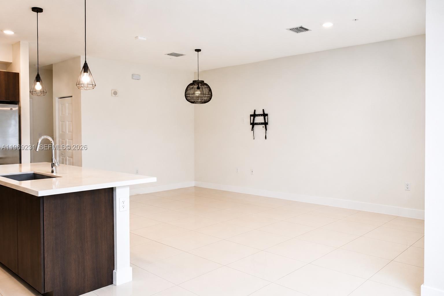 An open-concept kitchen and dining area features a dark wood island, pendant lighting, and tile flooring — 4745 NW 84th Ct # 14, Doral FL 33166, DORAL, FL