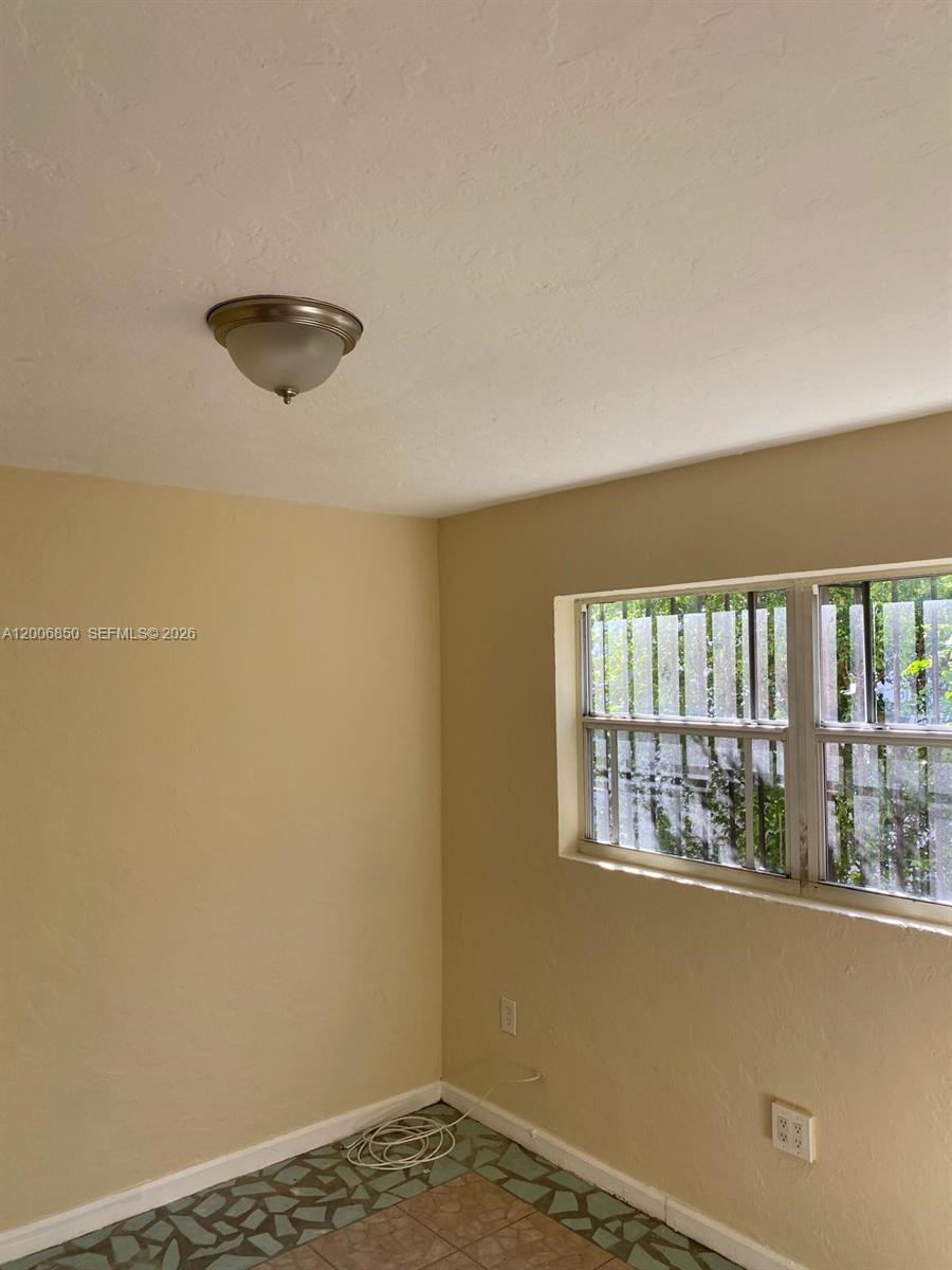 A room with beige walls, a flush-mount ceiling light, and tiled flooring — 1319 NW 60th St # 5, Miami FL 33142, MIAMI, FL