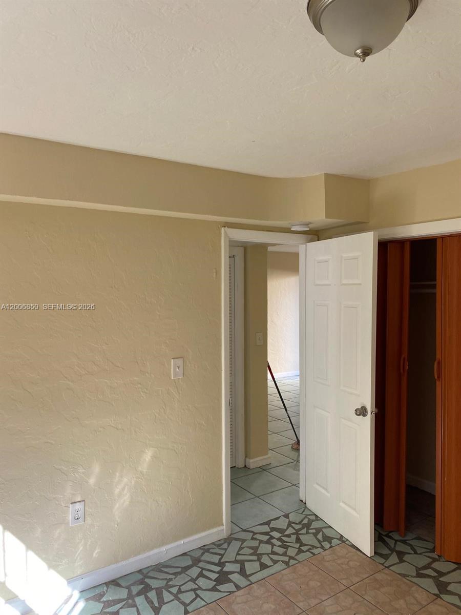 A room with beige walls, tiled flooring, a white door, and a closet — 1319 NW 60th St # 5, Miami FL 33142, MIAMI, FL