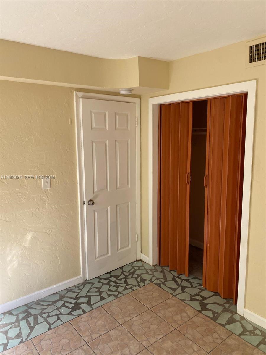A room features a white door, a wooden bifold closet door, and tiled flooring — 1319 NW 60th St # 5, Miami FL 33142, MIAMI, FL