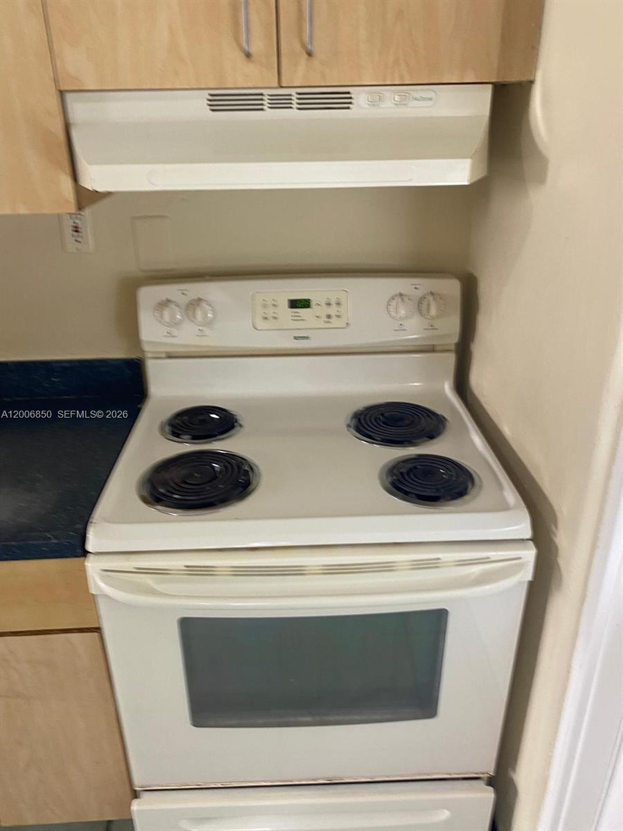 A white electric range sits beneath a matching range hood in a kitchen — 1319 NW 60th St # 5, Miami FL 33142, MIAMI, FL