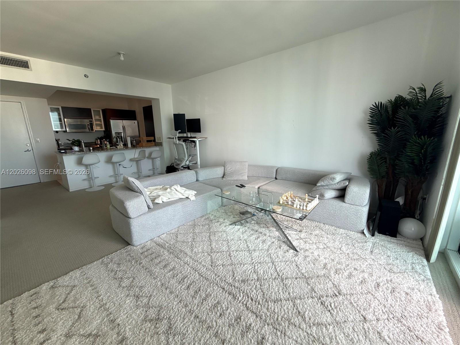 A living room features a light gray sectional sofa, a glass coffee table, and a rug — 951 Brickell Ave # 3703, Miami FL 33131, MIAMI, FL