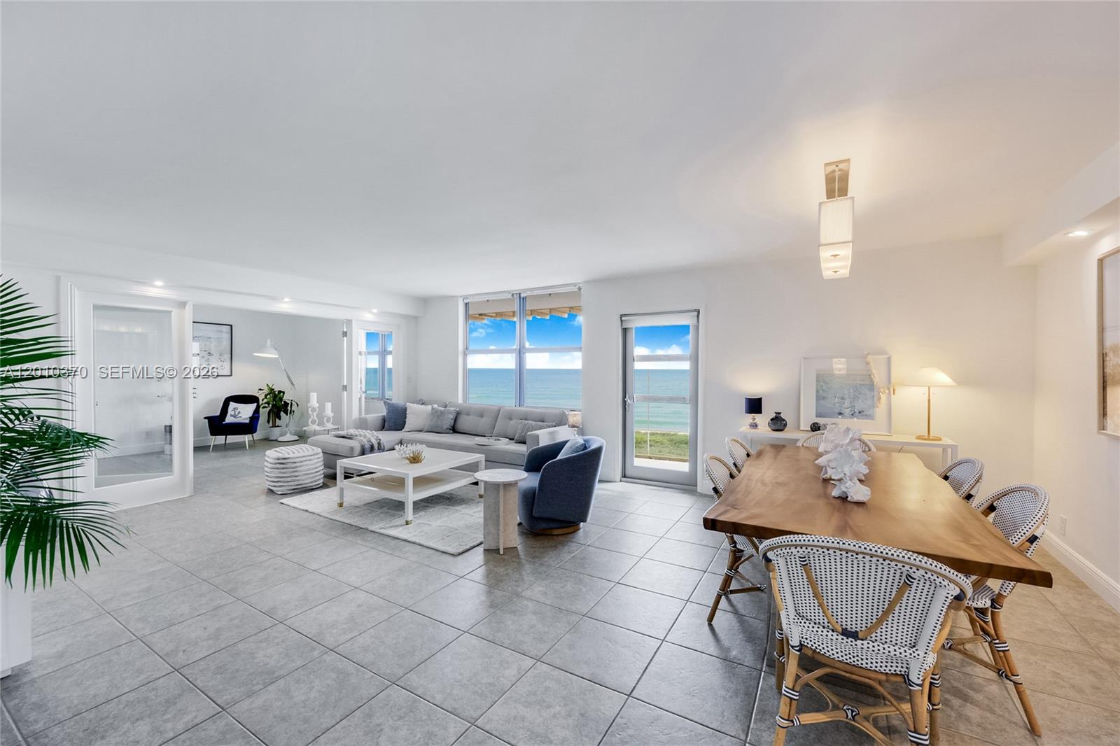 An open-concept living and dining area features tile floors, a gray sectional, and ocean views — 9225 Collins Ave # 501, Surfside FL 33154, SURFSIDE, FL