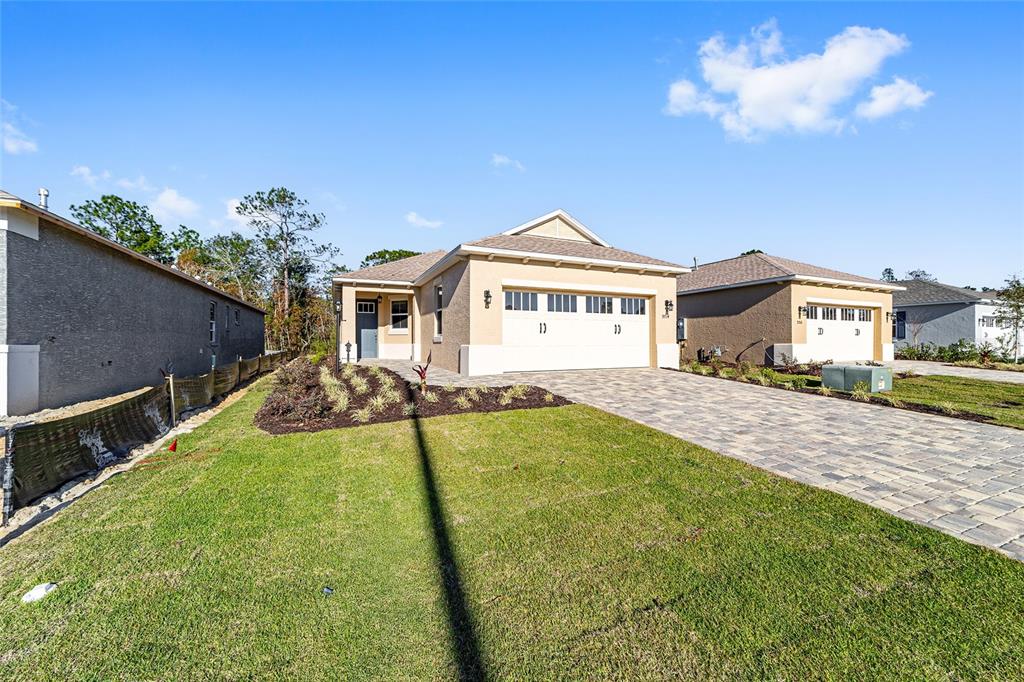 A tan single-story house with a two-car garage and a paved driveway — 9714 SW 108TH TERRACE ROAD, OCALA, FL