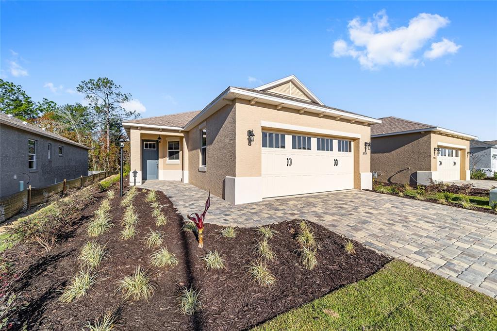 A single-story house with a beige stucco exterior, a two-car garage, and a paved driveway — 9714 SW 108TH TERRACE ROAD, OCALA, FL